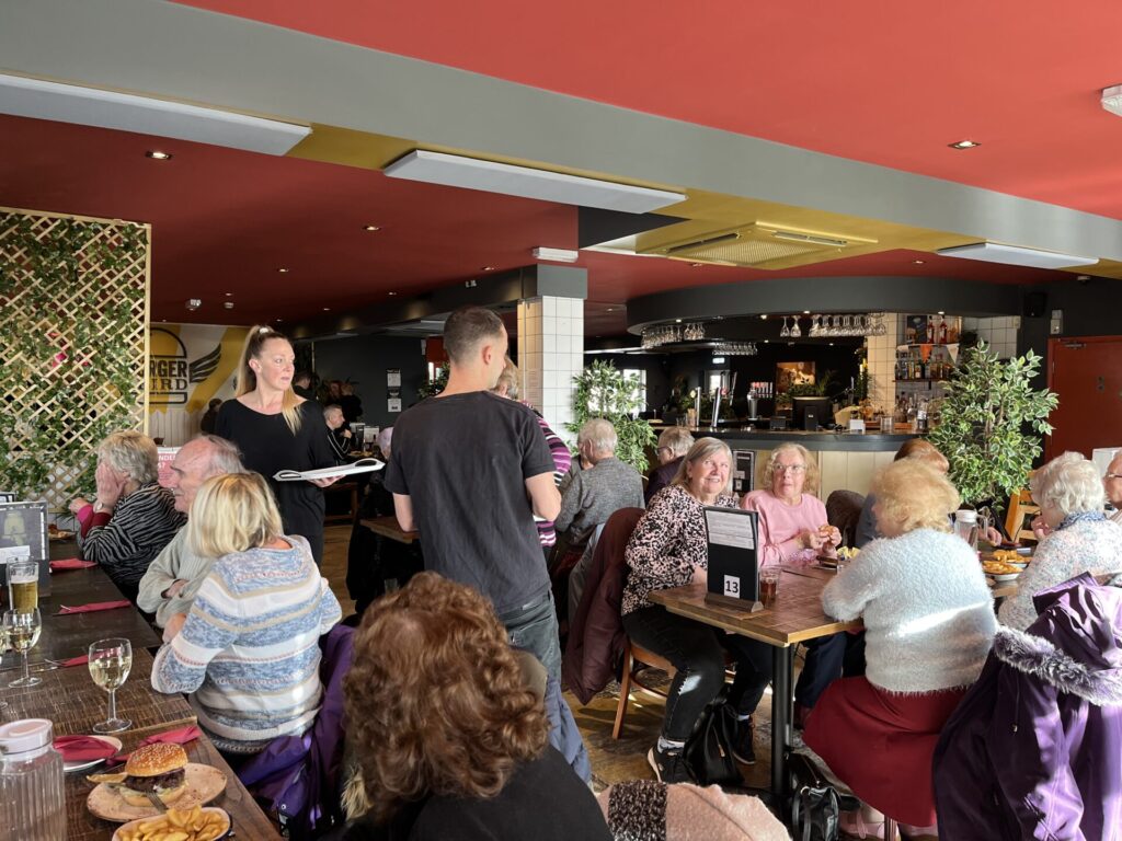 Many people eating lunch with waiters in attendance